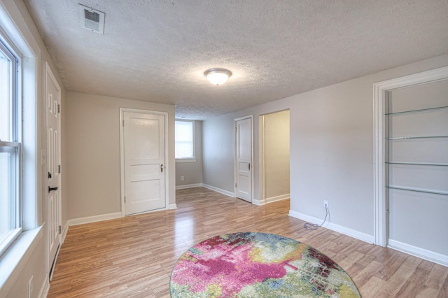 bedroom with a textured ceiling and light hardwood / wood-style flooring