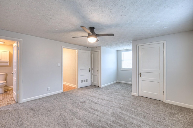 unfurnished bedroom with ensuite bathroom, light colored carpet, a textured ceiling, and ceiling fan