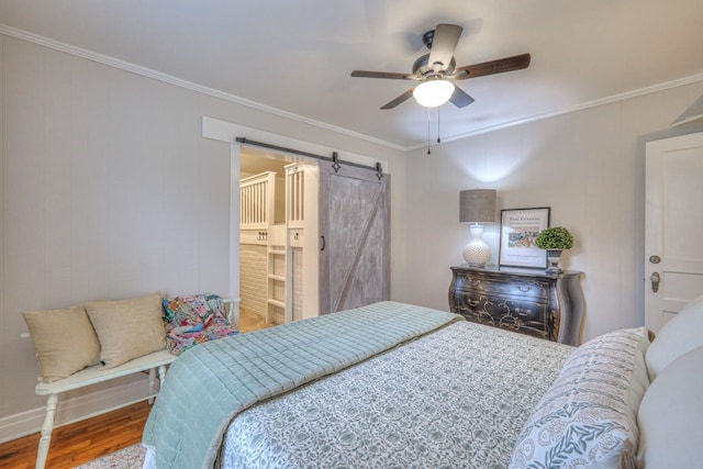 bedroom featuring hardwood / wood-style flooring, ornamental molding, a barn door, and ceiling fan