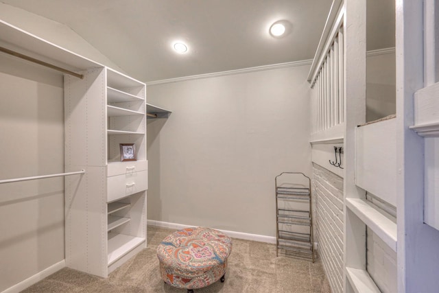 walk in closet with light carpet and vaulted ceiling