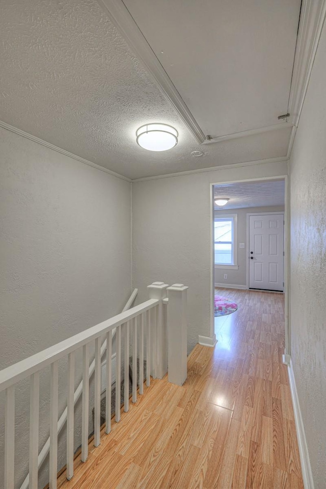 hall with hardwood / wood-style flooring, ornamental molding, and a textured ceiling