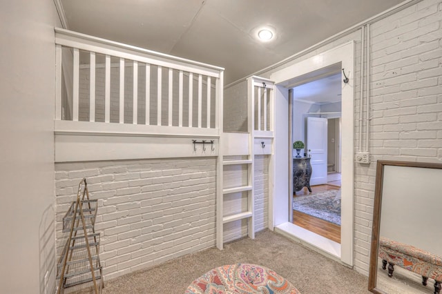 carpeted bedroom featuring ornamental molding and brick wall