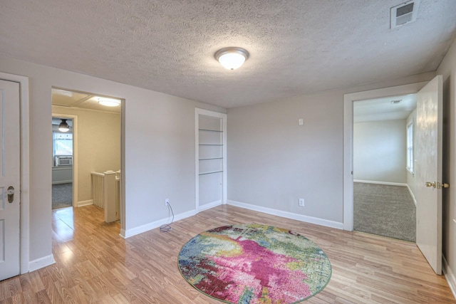 empty room with light hardwood / wood-style flooring and a textured ceiling