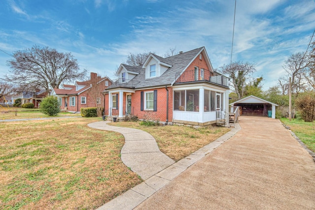 cape cod home with a carport, a balcony, a sunroom, and a front lawn