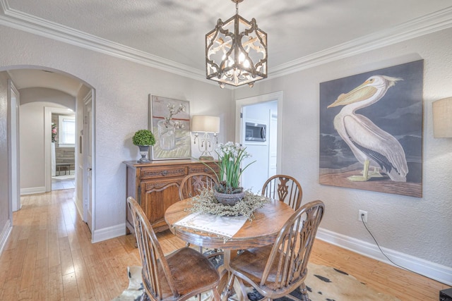 dining room with an inviting chandelier, light hardwood / wood-style flooring, ornamental molding, and a textured ceiling