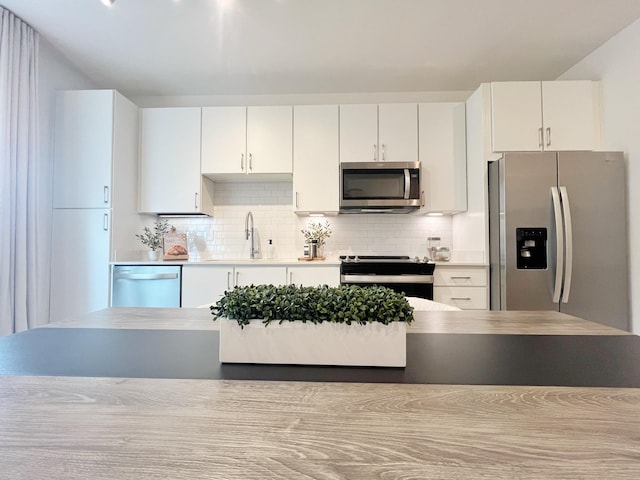 kitchen with decorative backsplash, stainless steel appliances, white cabinetry, and sink