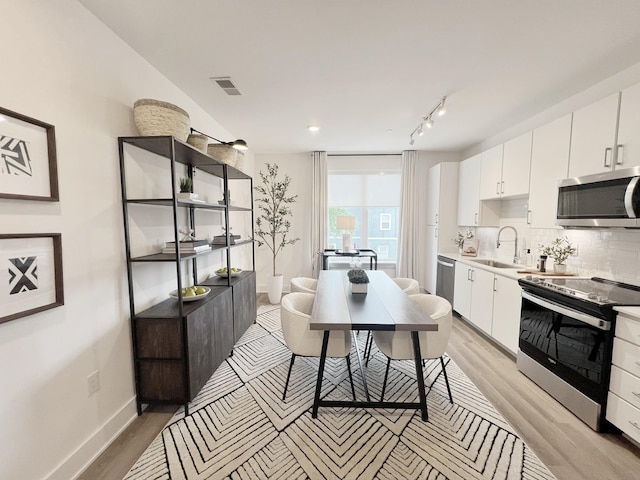 kitchen with light hardwood / wood-style floors, sink, white cabinetry, and stainless steel appliances