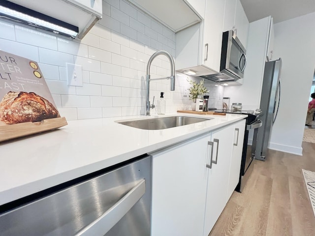 kitchen featuring white cabinets, sink, stainless steel appliances, and tasteful backsplash