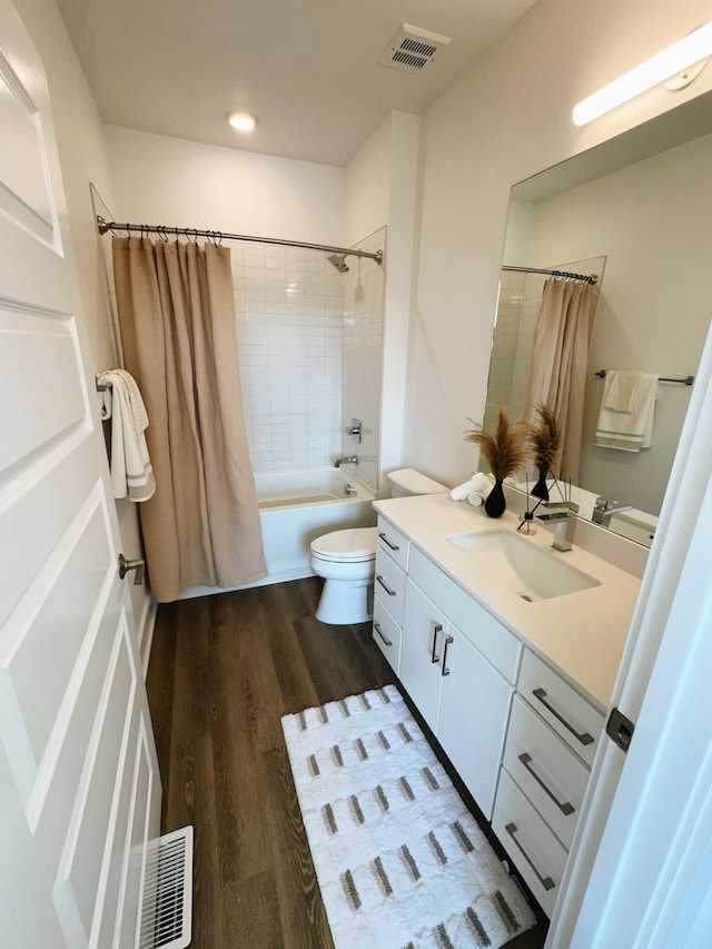 full bathroom with hardwood / wood-style floors, vanity, shower / tub combo, and toilet