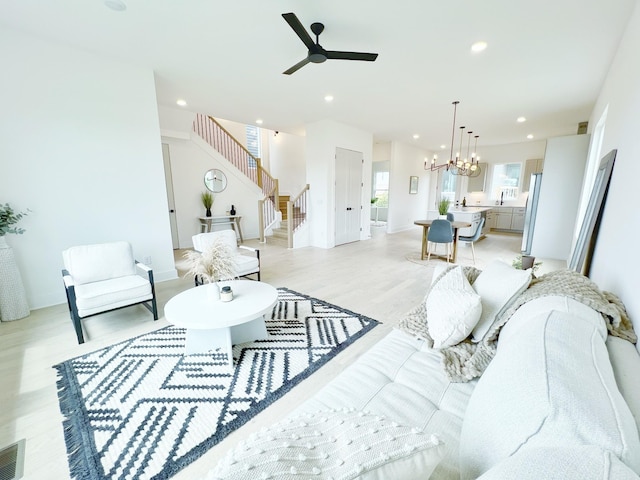 living room with light hardwood / wood-style floors and ceiling fan with notable chandelier