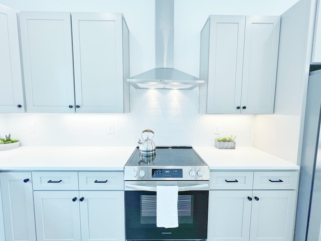 kitchen with wall chimney exhaust hood, decorative backsplash, and appliances with stainless steel finishes