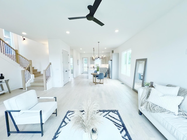 living room featuring light wood-type flooring and ceiling fan with notable chandelier