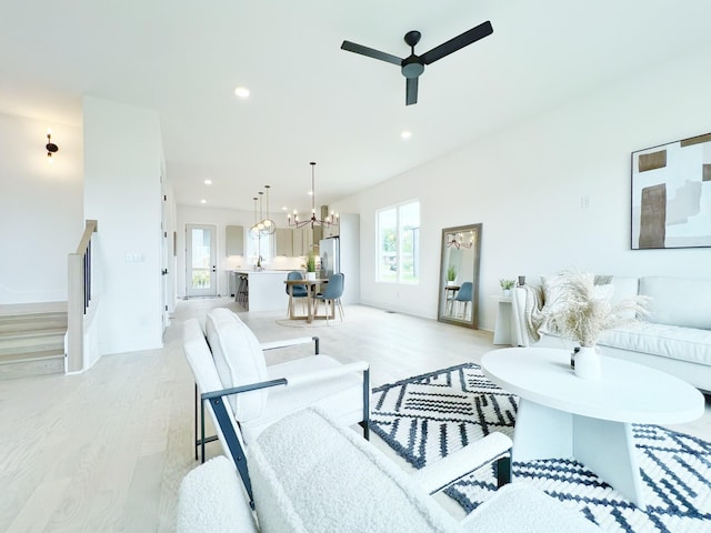 living room with ceiling fan with notable chandelier and light hardwood / wood-style floors