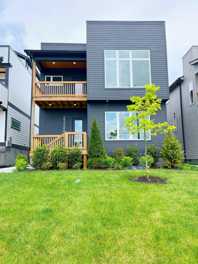 rear view of house with a lawn and a balcony