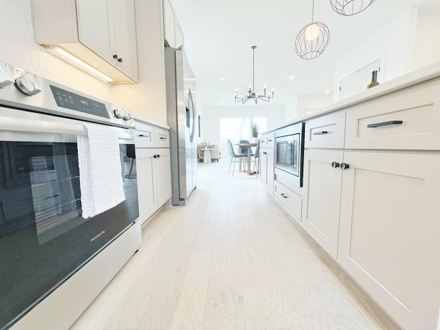 kitchen featuring appliances with stainless steel finishes, pendant lighting, a chandelier, white cabinets, and light wood-type flooring