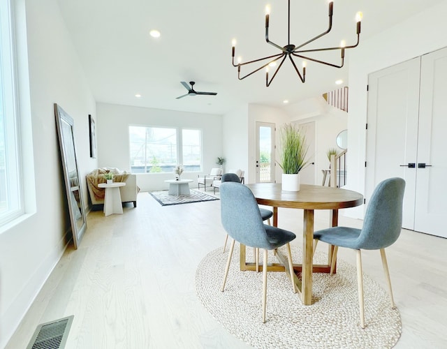 dining area featuring light hardwood / wood-style floors and ceiling fan with notable chandelier