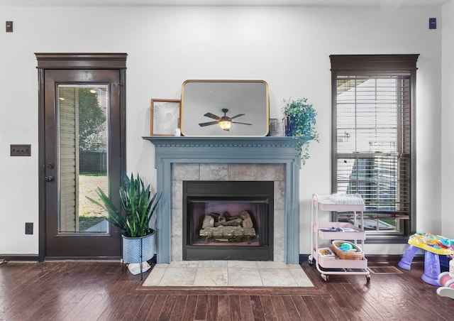 interior space featuring ceiling fan, wood-type flooring, and a tiled fireplace