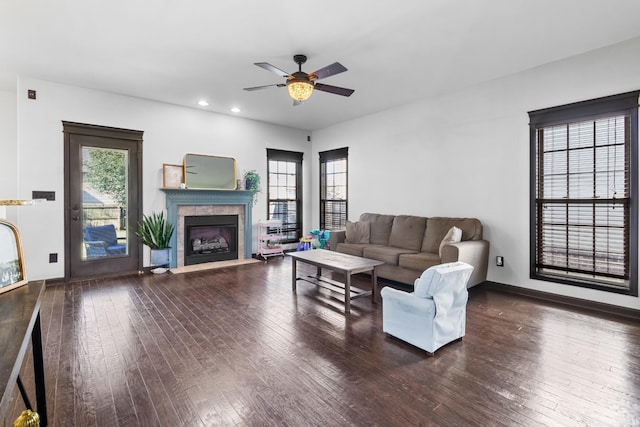 living room featuring a wealth of natural light, dark hardwood / wood-style flooring, ceiling fan, and a tiled fireplace