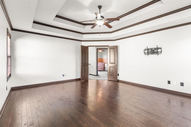 empty room featuring ceiling fan, dark hardwood / wood-style flooring, ornamental molding, and a tray ceiling