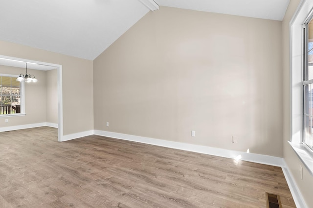 unfurnished room featuring hardwood / wood-style floors, lofted ceiling with beams, and an inviting chandelier