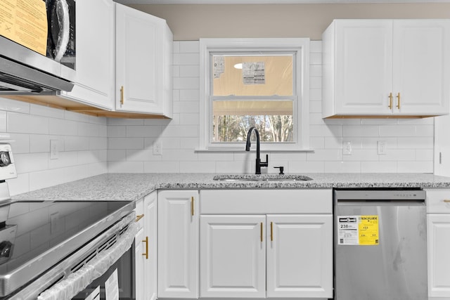 kitchen with white cabinets, light stone counters, sink, and stainless steel appliances