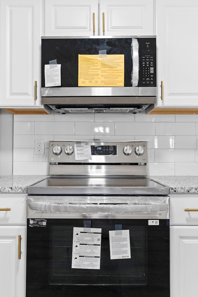 kitchen featuring white cabinets, appliances with stainless steel finishes, and light stone countertops