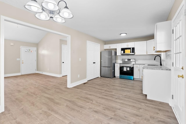 kitchen featuring white cabinetry, sink, light stone countertops, hanging light fixtures, and stainless steel appliances