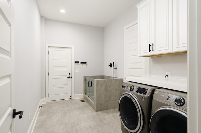 laundry area featuring washing machine and dryer, light tile patterned floors, and cabinets