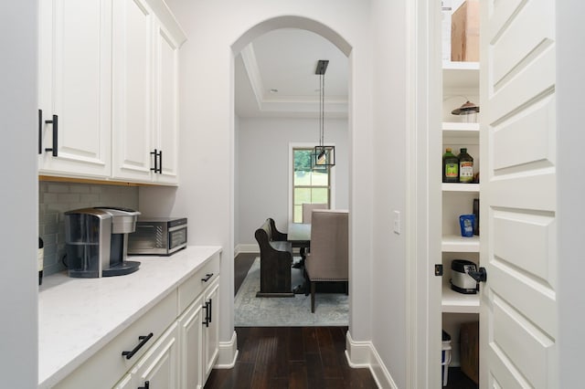 bar with white cabinetry, light stone countertops, hanging light fixtures, dark hardwood / wood-style floors, and decorative backsplash