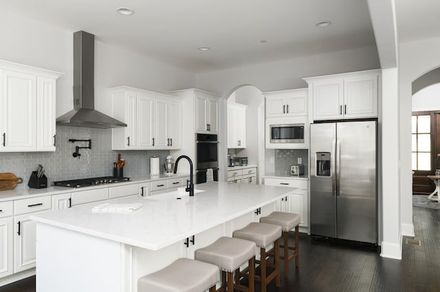 kitchen with wall chimney exhaust hood, white cabinetry, sink, and appliances with stainless steel finishes