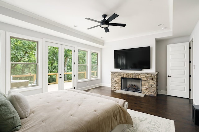 bedroom featuring access to outside, a stone fireplace, ceiling fan, and dark hardwood / wood-style floors