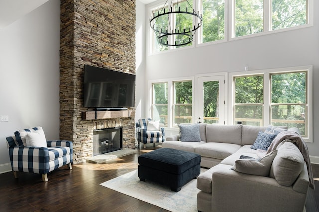 living room featuring a high ceiling, an inviting chandelier, a stone fireplace, and a healthy amount of sunlight