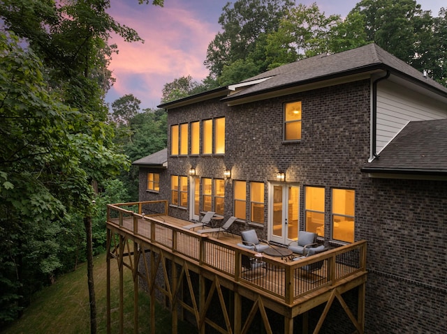 back house at dusk featuring a wooden deck