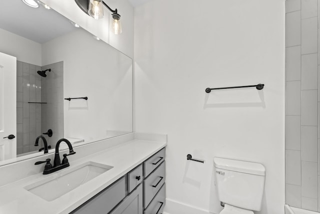 bathroom featuring a tile shower, vanity, and toilet