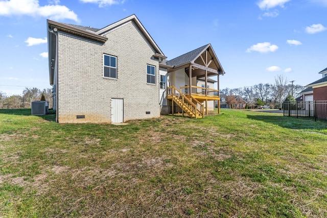 back of property with central AC unit, a wooden deck, and a lawn