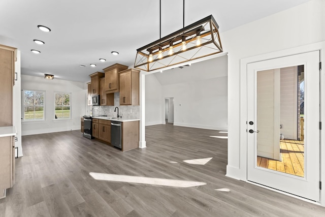 kitchen with sink, stainless steel appliances, dark wood-type flooring, backsplash, and pendant lighting