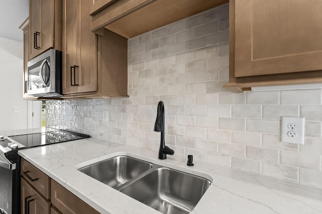 kitchen featuring sink, light stone countertops, stainless steel appliances, and tasteful backsplash