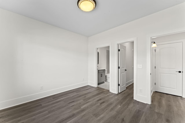 unfurnished bedroom featuring connected bathroom and dark wood-type flooring