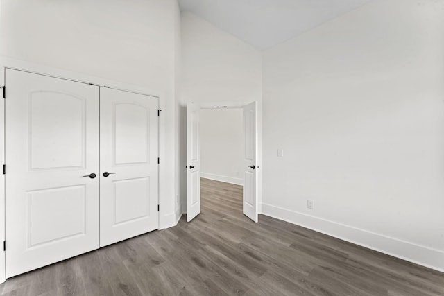 unfurnished bedroom featuring a closet, high vaulted ceiling, and hardwood / wood-style floors