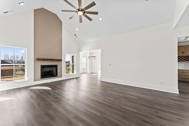 unfurnished living room featuring ceiling fan, a large fireplace, dark wood-type flooring, and high vaulted ceiling