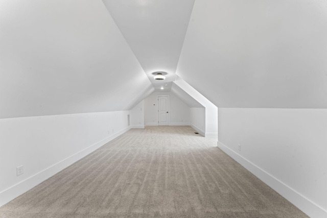 additional living space featuring light colored carpet and vaulted ceiling