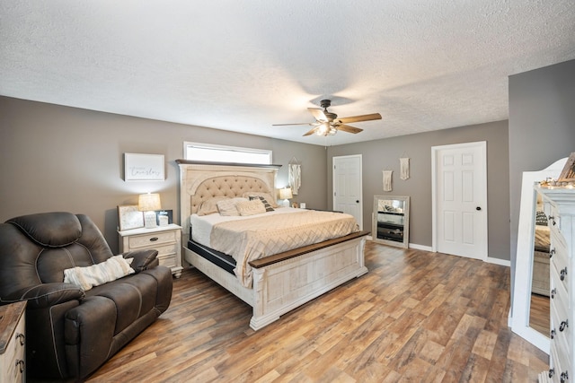 bedroom featuring ceiling fan, wood-type flooring, and a textured ceiling