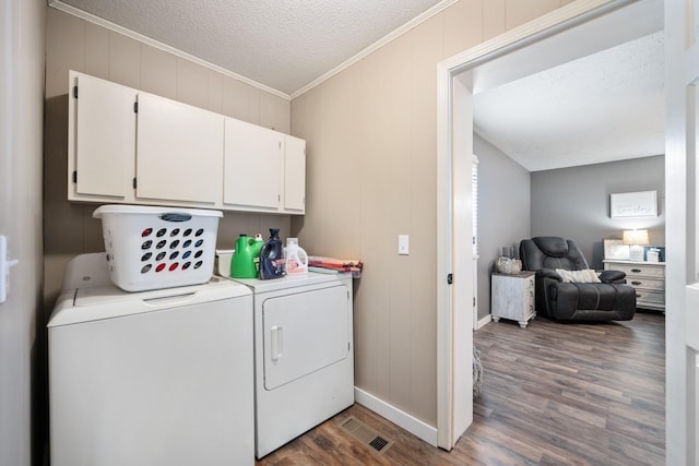 laundry room featuring cabinets, dark hardwood / wood-style floors, crown molding, a textured ceiling, and washer and dryer