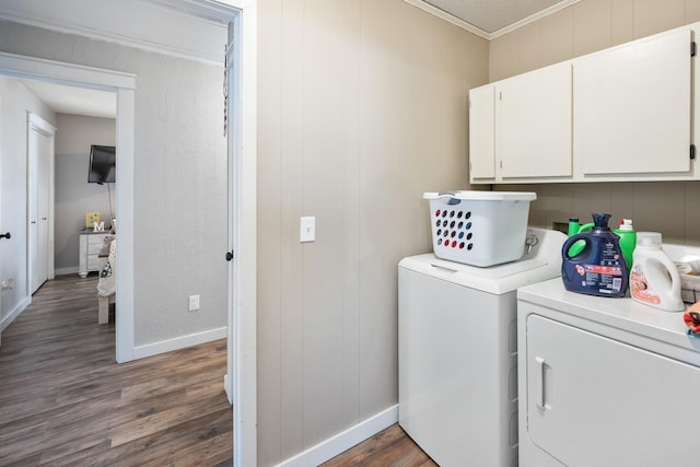 clothes washing area featuring washer and clothes dryer, crown molding, cabinets, and dark wood-type flooring