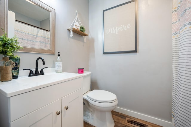 bathroom with wood-type flooring, vanity, and toilet