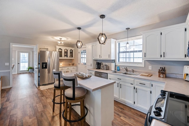 kitchen with a center island, stainless steel appliances, white cabinetry, and sink