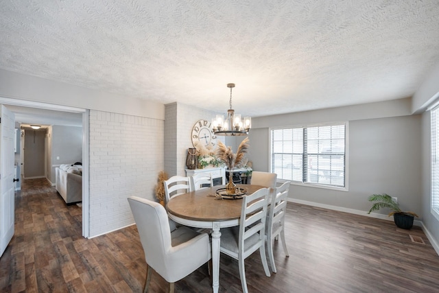 dining room featuring a textured ceiling, dark hardwood / wood-style flooring, an inviting chandelier, and brick wall