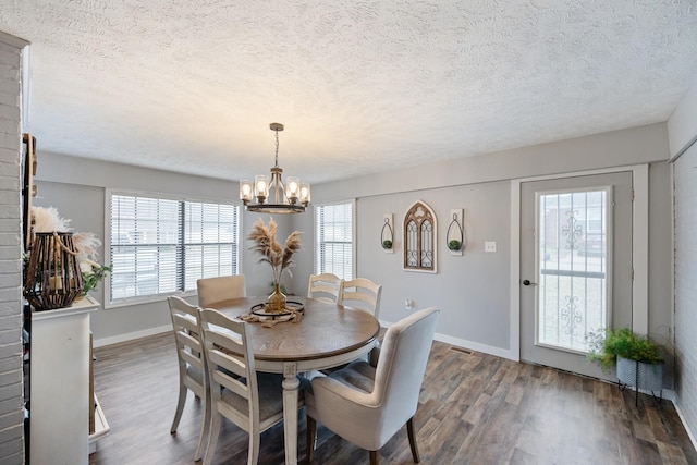 dining area with a textured ceiling, dark hardwood / wood-style floors, and an inviting chandelier