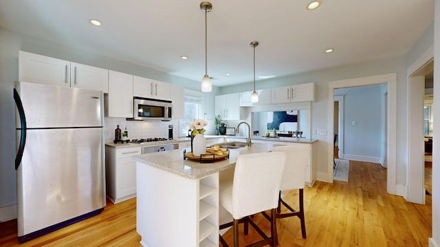 kitchen featuring white cabinetry, sink, an island with sink, decorative backsplash, and appliances with stainless steel finishes