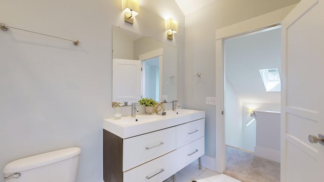 bathroom with tile patterned flooring, vanity, toilet, and lofted ceiling with skylight